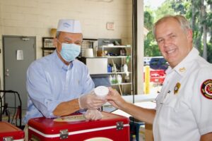 Stratton Leopold of Leopold’s Ice Cream hands an ice cream to Chuck Kearns, Chief Executive Officer of Chatham Emergency Services.