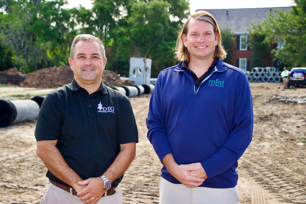 Chris Tilton, co-principal of Dewitt Tilton Group (left), stands with R. Daniel Blanton, Jr., co-owner of Mint Car Wash (right) on the construction site of the new Mint Car Wash building. Not pictured: Robert Wilson, co-owner of Mint Car Wash.